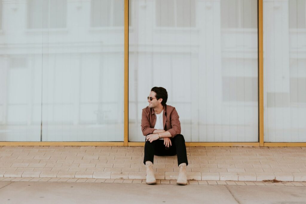 Woman sits on the floor looking thoughtful amidst a room full of packed cardboard moving boxes, representing the mental an...